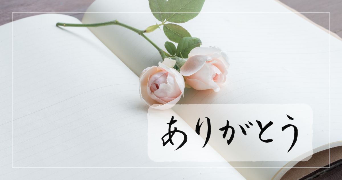 薔薇の花と開いたをノートを背景に、「ありがとう」の筆文字