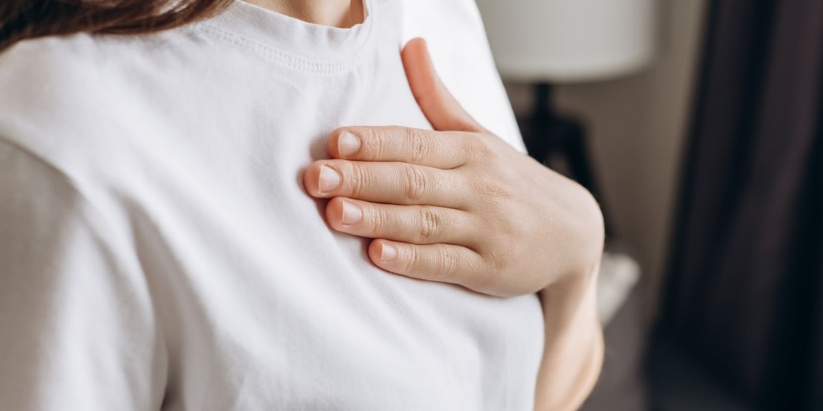 女性が胸にそっと左手を置いている。