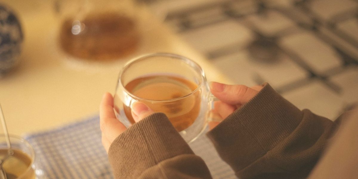 女性が、両手でコーヒーカップを持っている。