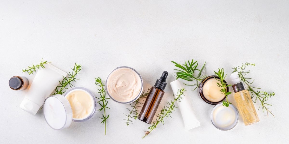 白い背景に化粧品と緑の植物が並んでいる。