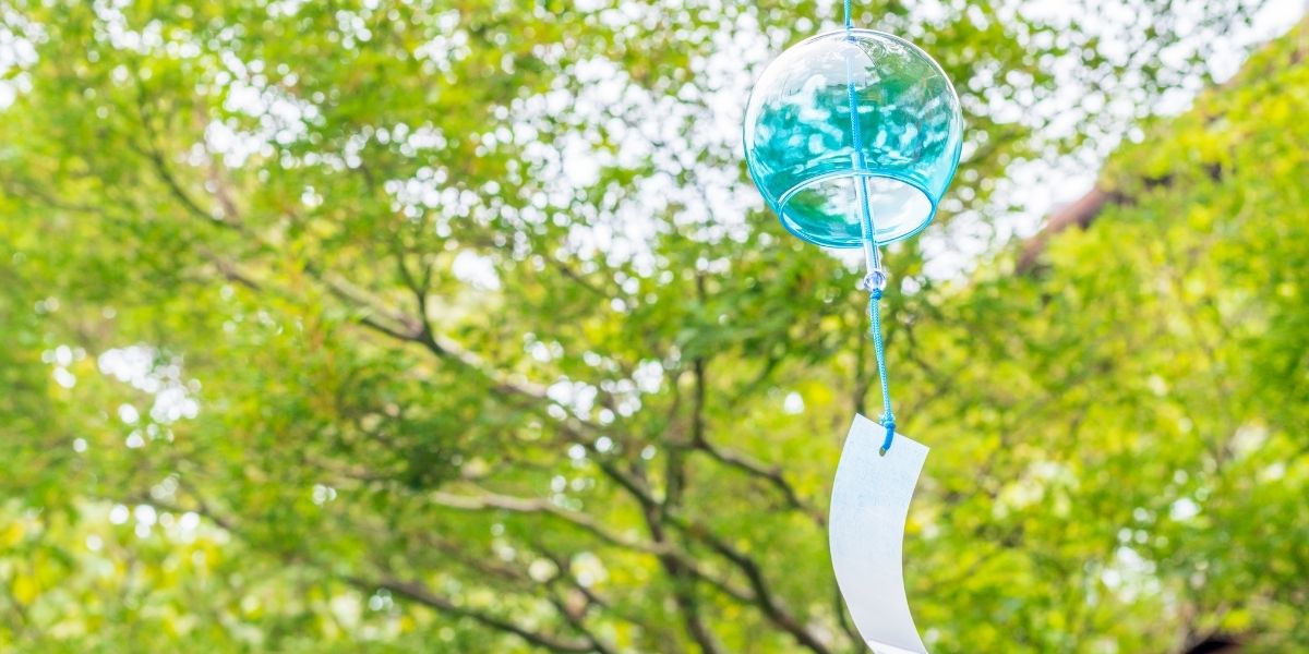 自然の木々を背景にして、優しく揺れる涼しげな風鈴。