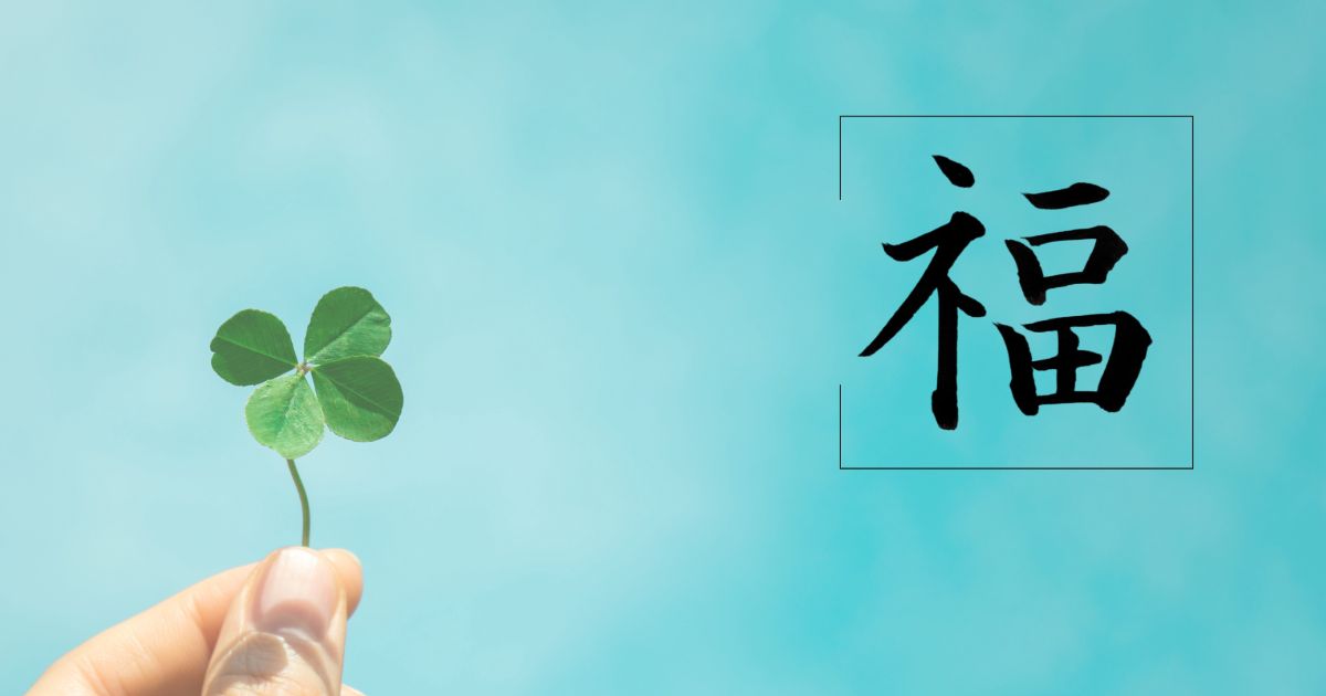 筆文字「福」。廃鶏には黄色く可憐なフクジュソウが咲いている。