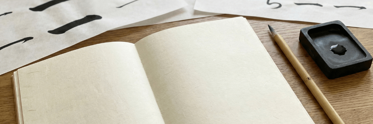 筆と硯と開かれたノート。何度も練習した後が伺える紙。