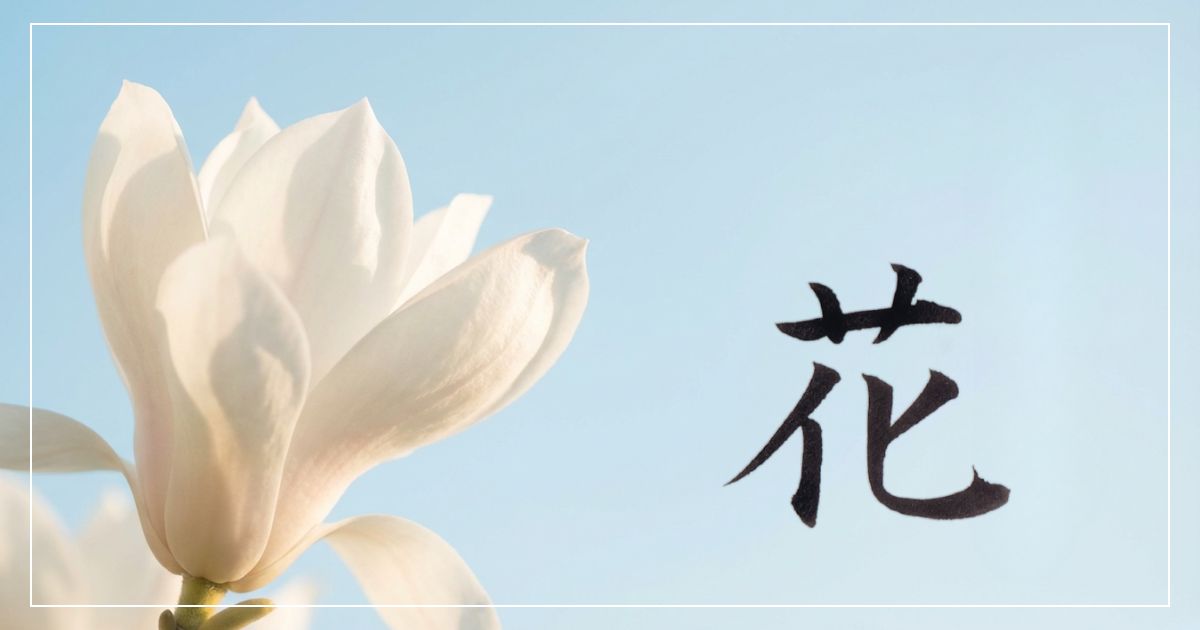 青空を背景に、真っ白なハクモクレンと「花」の筆文字