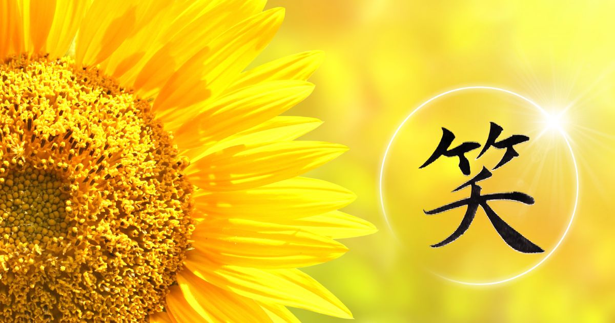 「笑」背景に燃えるような明るいひまわりのアップ。