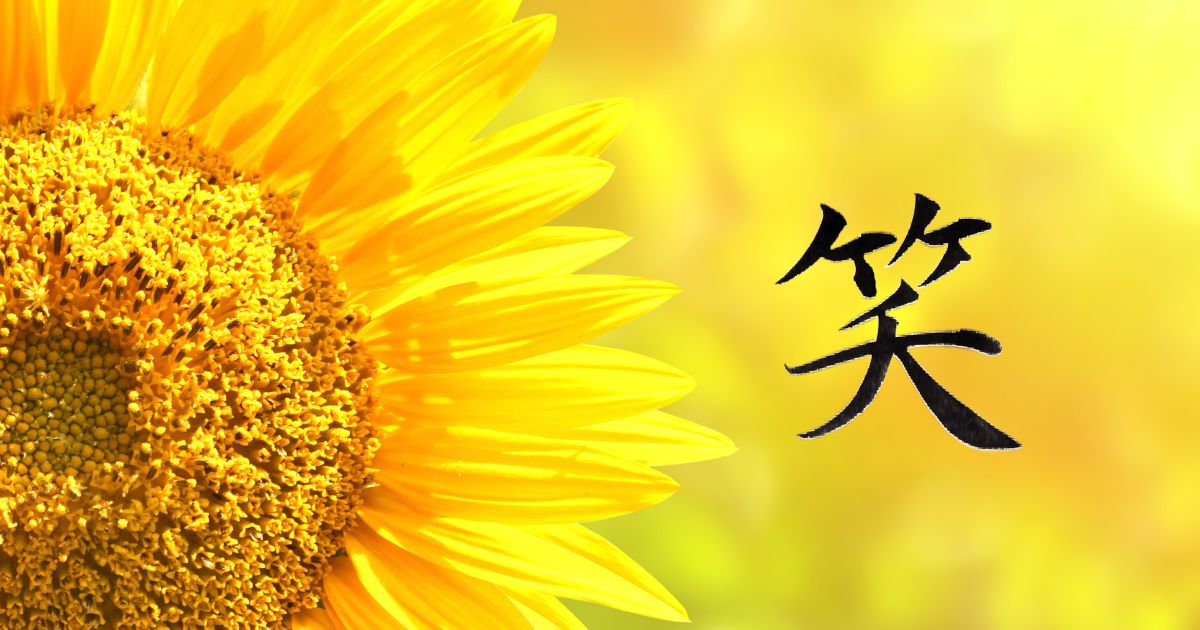 「笑」背景に燃えるような明るいひまわりのアップ。