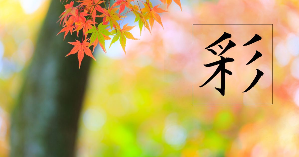 筆文字「彩」。背景には美しい紅葉が青から赤へと紅葉している様子。