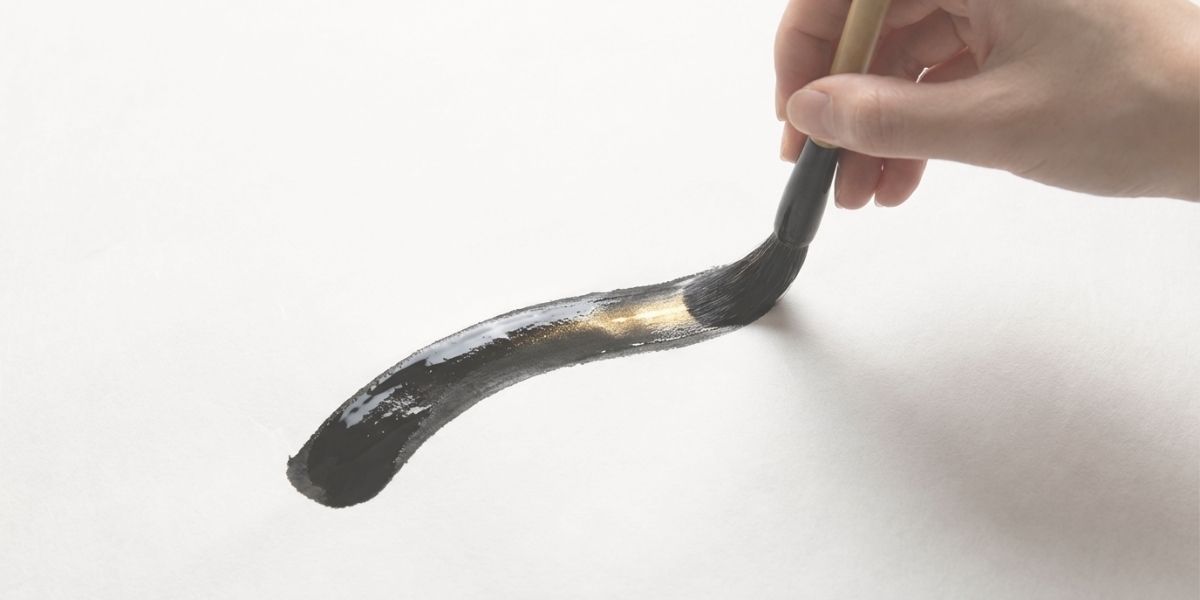 筆で、白い紙に文字を書きだした様子。