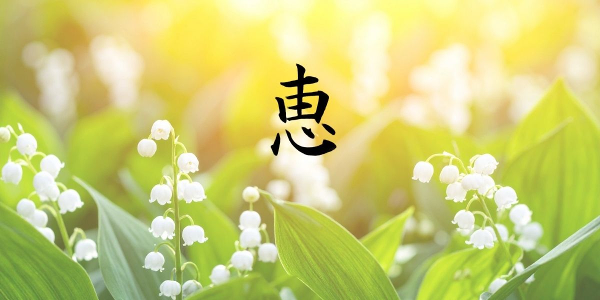 筆文字「恵」。背景には、白い可憐なスズランの群生。