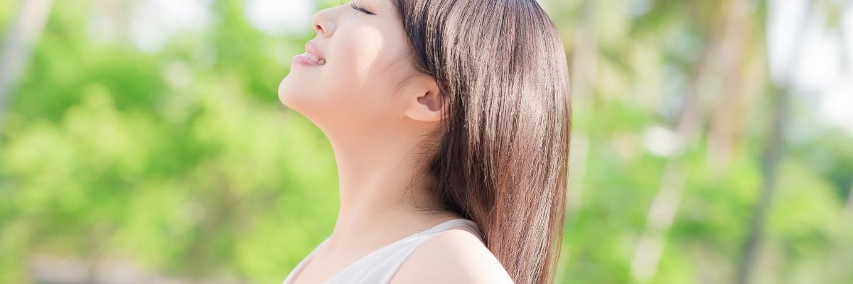 希望に満ち溢れた表情で自然の中で深呼吸している女性