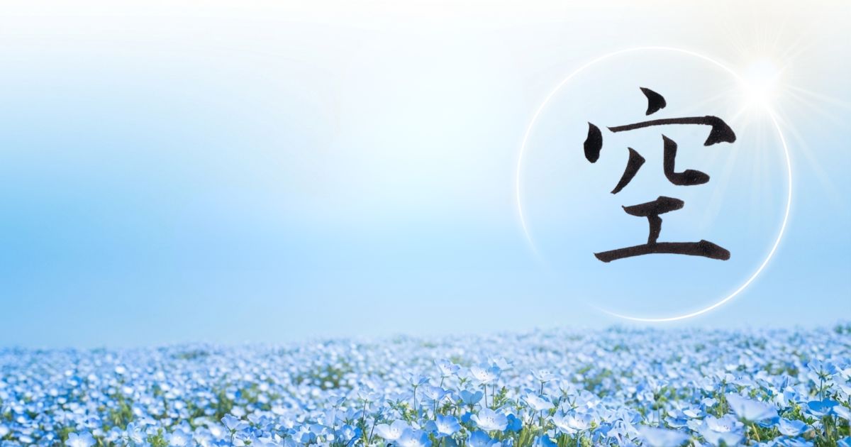 真っ青な空と一面のネモフィラを背景に、漢字「空」の筆文字