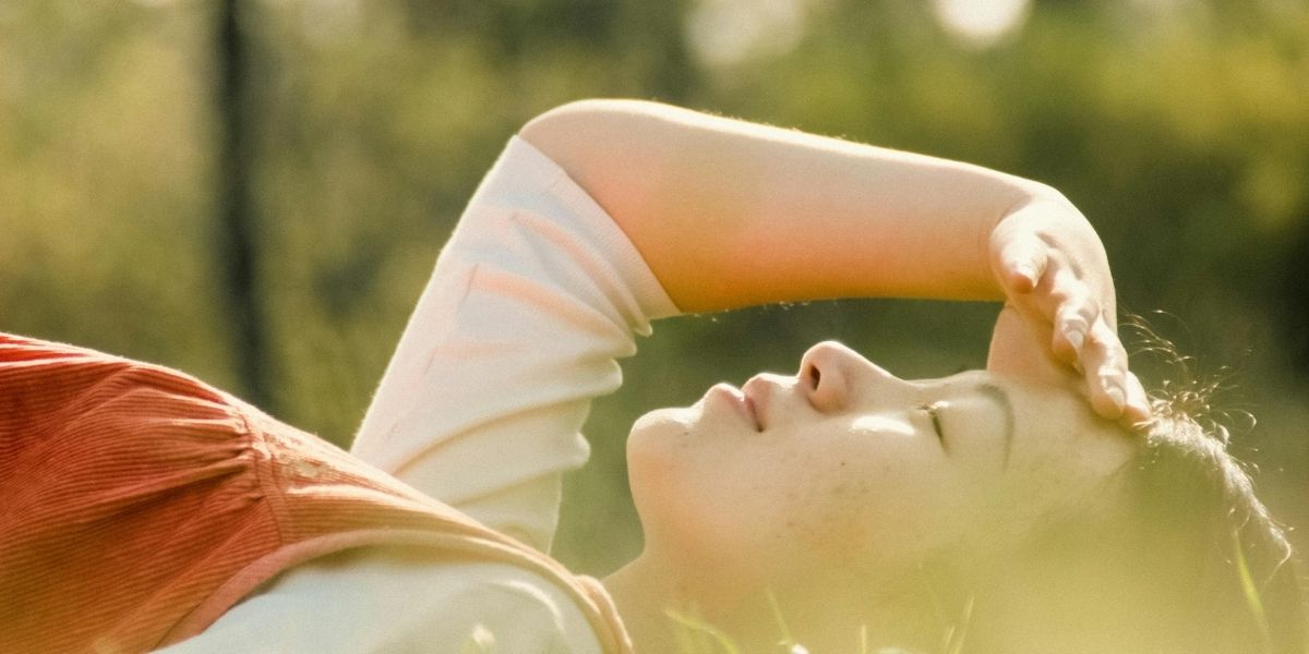 草原の中で気持ちよさそうに寝転んでいる女性。