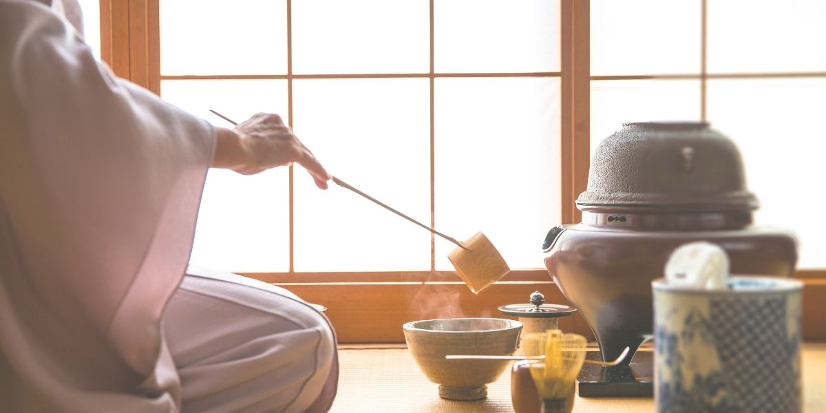 女性が茶道でお茶をたてている様子。背景には障子。