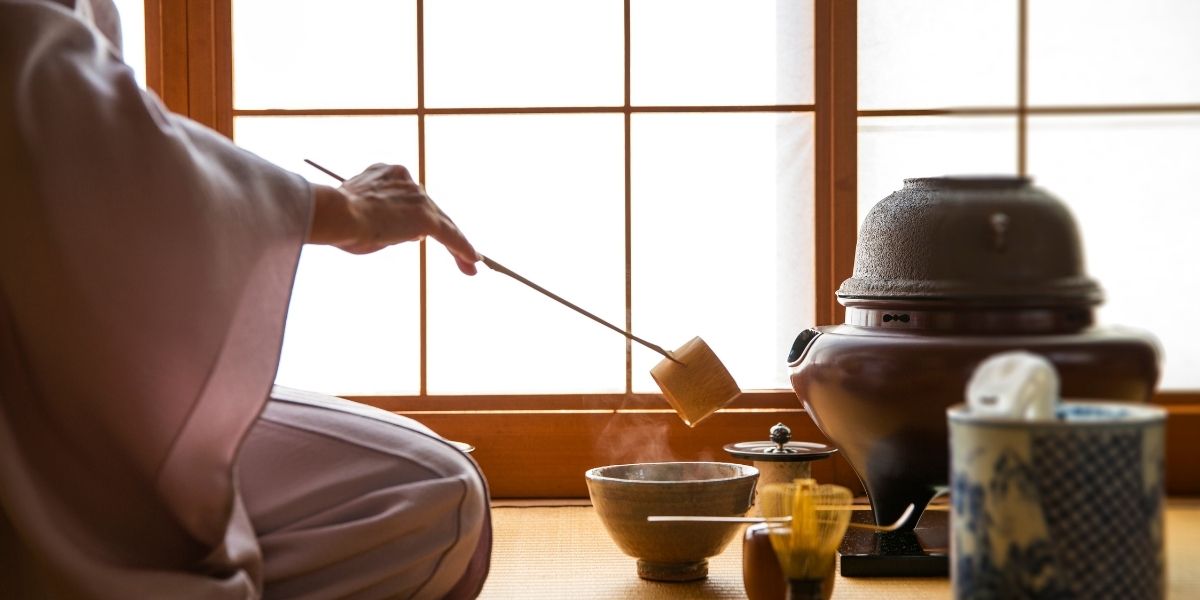 女性が茶道でお茶をたてている様子。背景には障子。